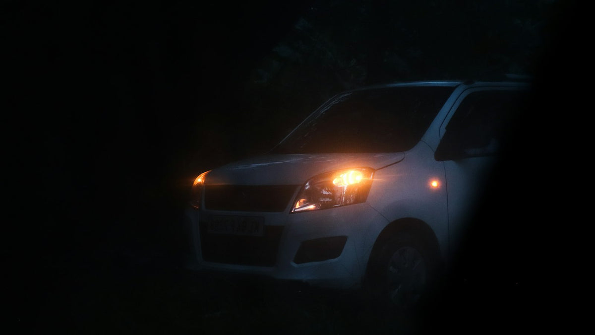 a white car with its lights on in the dark