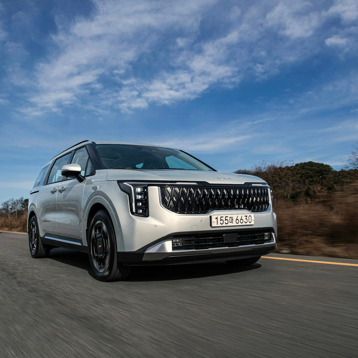 a white car driving down a road under a blue sky