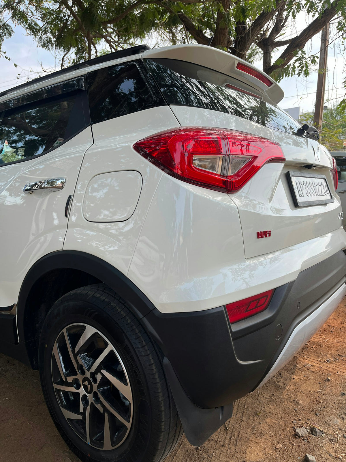 the rear end of a white suv parked on a dirt road