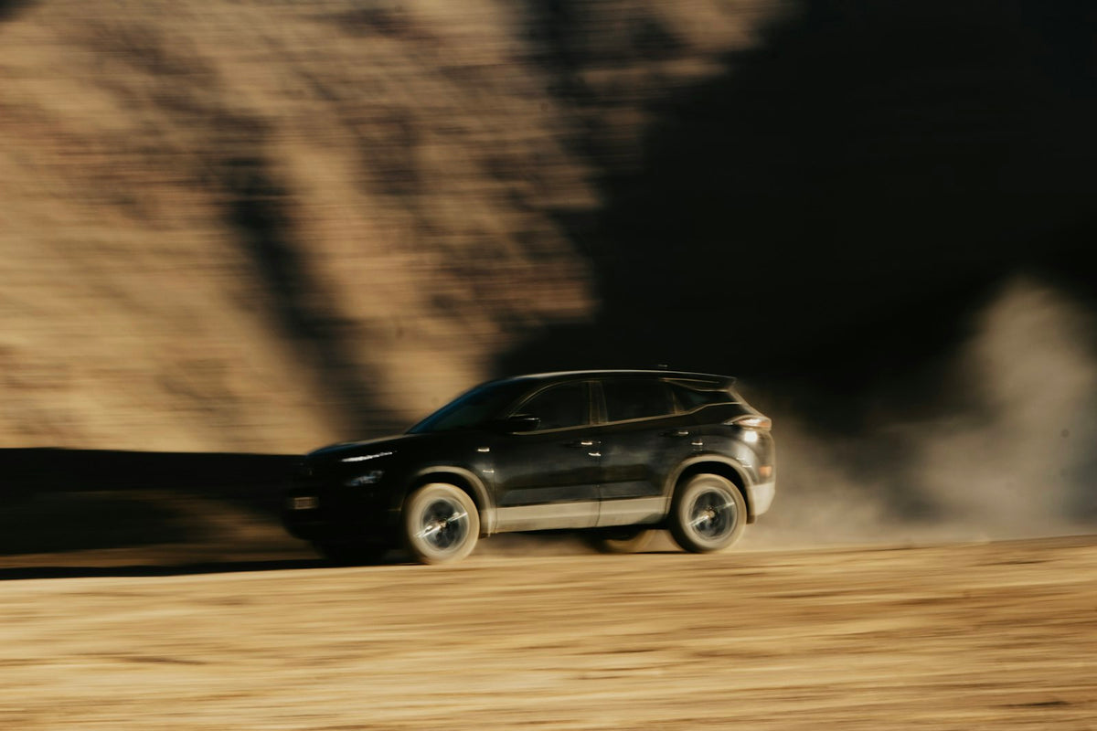 A black suv driving down a dirt road