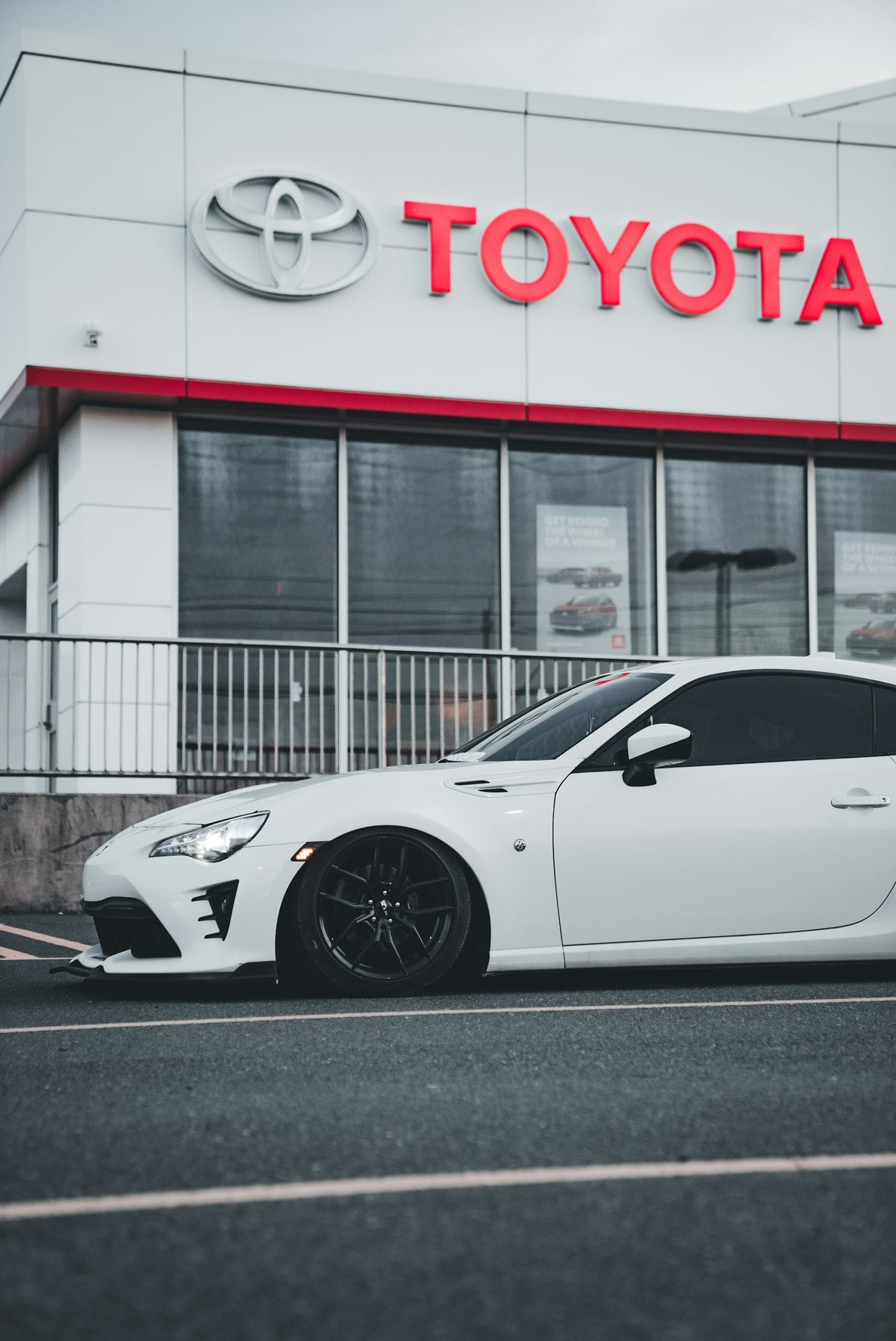 A white sports car parked in front of a toyota dealership